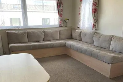 a living room with a large couch in front of a window at Newquay - Pet Friendly 6 Berth Caravan in Newquay