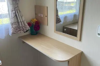 a counter in a room with a mirror and flowers at Newquay - Pet Friendly 6 Berth Caravan in Newquay