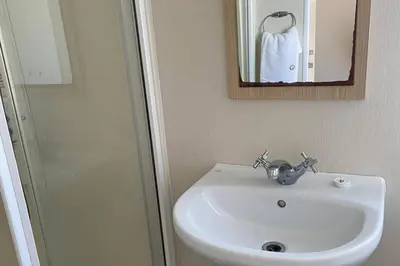 a bathroom with a sink and a shower and a mirror at Newquay - Pet Friendly 6 Berth Caravan in Newquay