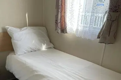 a bed with white pillows and a window at Newquay - Pet Friendly 6 Berth Caravan in Newquay