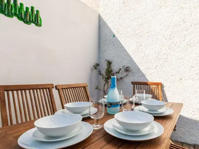 a wooden table with plates and bowls and wine glasses at Holiday Home Seaforth by Interhome in Gorran Haven
