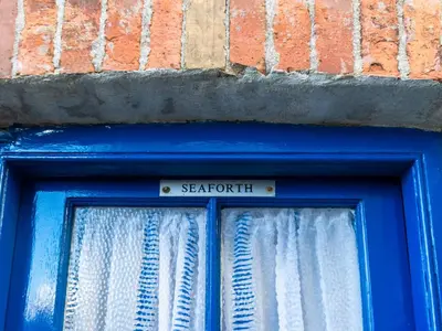 a blue door with a sign that says sartori at Holiday Home Seaforth by Interhome in Gorran Haven
