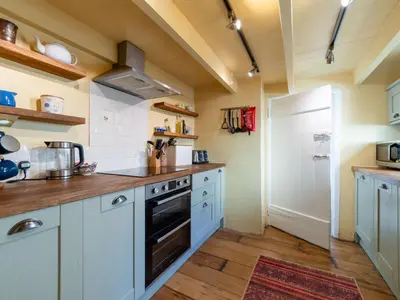 a kitchen with white cabinets and a stove top oven at Holiday Home Seaforth by Interhome in Gorran Haven