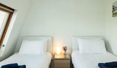 two beds in a room with a candle on a table at 6 Slipway in Padstow