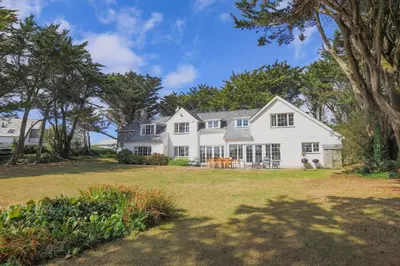 a large white house with a large yard at Trewidden in Polzeath