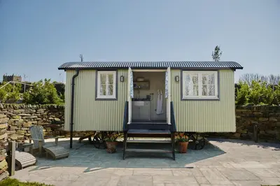 a green tiny house on a patio at Shepherds Huts at The Cornish Arms in St Merryn