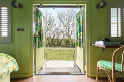 an open door into a room with green walls at Shepherds Huts at The Cornish Arms in St Merryn