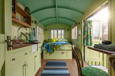 a kitchen with a bed and a green ceiling at Shepherds Huts at The Cornish Arms in St Merryn