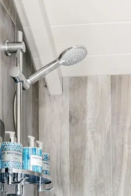 a bathroom sink with a shower head and toothbrushes at Shepherds Huts at The Cornish Arms in St Merryn