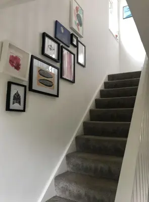a staircase with framed pictures on the wall at Stylish Room Close to Beaches in Falmouth