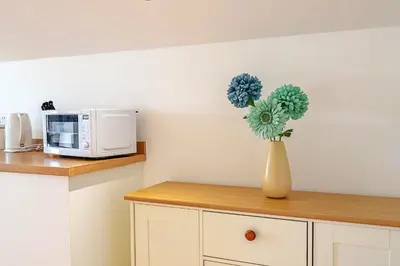 a vase with blue flowers on a counter in a kitchen at Finest Retreats - Stable Barn Apartment at Bodmin Moor in Saint Breward