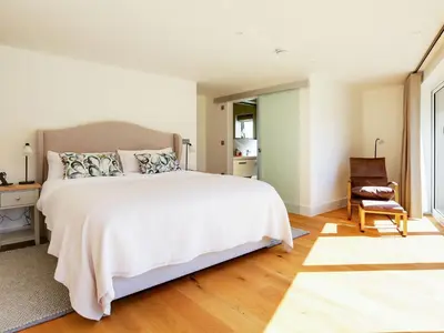 a bedroom with a large white bed and a chair at 1 Zeath in Polzeath