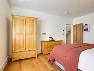 a bedroom with a bed and a wooden cabinet at 1 Zeath in Polzeath