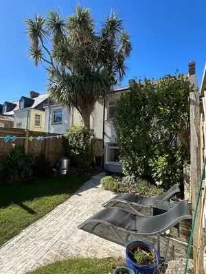 a yard with a fence and a palm tree at Palm Haven House - Luxury family-friendly Newquay surf house near Porth Beach perfect for walking, pets, exploring in Newquay