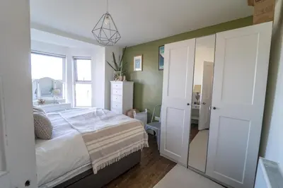 a bedroom with a large white bed and a window at Palm Haven House - Luxury family-friendly Newquay surf house near Porth Beach perfect for walking, pets, exploring in Newquay