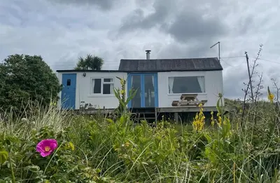a small house with a blue door in a field at Sunset Sea Views 1 min to beach On SW Coast Path Private Parking in Uny Lelant