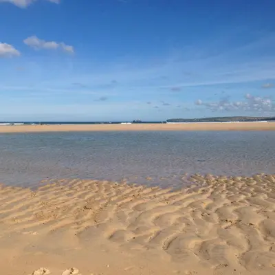 a sandy beach with a body of water at Sunset Sea Views 1 min to beach On SW Coast Path Private Parking in Uny Lelant