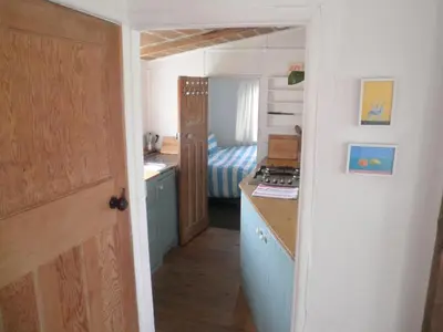 a kitchen with a sink and a room with a bed at Sunset Sea Views 1 min to beach On SW Coast Path Private Parking in Uny Lelant