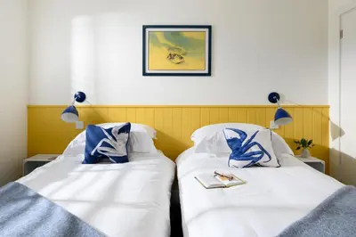 two beds in a room with white and blue pillows at 17 Slipway in Padstow