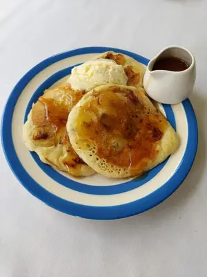 a blue and white plate with pancakes with eggs and syrup at Boscastle House in Boscastle