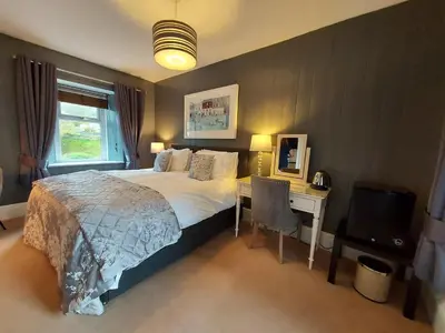 a bedroom with a bed and a desk and a television at Boscastle House in Boscastle