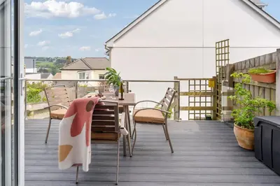 a patio with a table and chairs on a balcony at Peaceful Harbour-View Cottage - Tresellick Gardens in Flushing