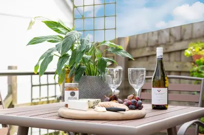 a table with a bottle of wine and wine glasses at Peaceful Harbour-View Cottage - Tresellick Gardens in Flushing