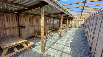 a row of picnic tables and benches in a pavilion at Celtic Longhouse Tent at Coverack Camping in Coverack