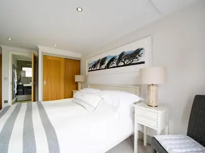 a white bedroom with a white bed and a chair at 11 Slipway in Padstow