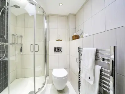 a white bathroom with a shower and a toilet at 11 Slipway in Padstow