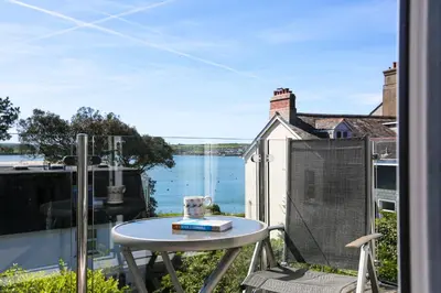 a table and chair on a balcony with a view of the water at 11 Slipway in Padstow