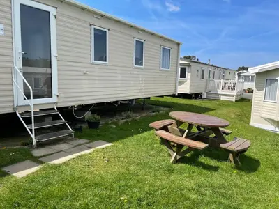 a table and a picnic table in front of a caravan at Caravan 163 sleeps up to 8 guests in Newquay