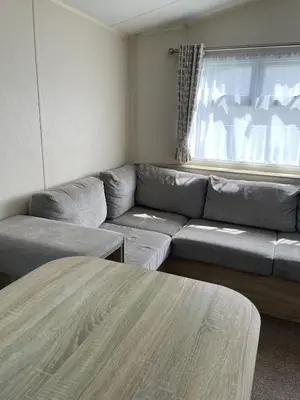 a living room with a couch and a window at Caravan 163 sleeps up to 8 guests in Newquay