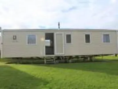 a large white mobile home sitting in a field at Caravan 163 sleeps up to 8 guests in Newquay