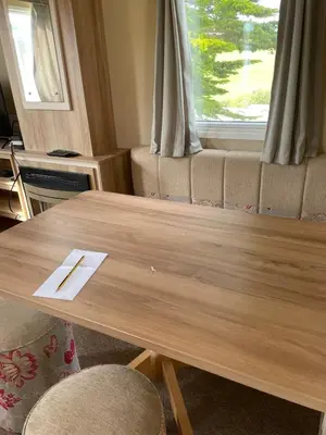 a wooden table in a living room with a window at Caravan 163 sleeps up to 8 guests in Newquay