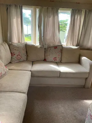 a white couch sitting in front of a window at Caravan 163 sleeps up to 8 guests in Newquay