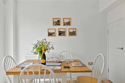 a dining room table with white chairs and a bottle of wine at Finest Retreats - Cove House in St Austell