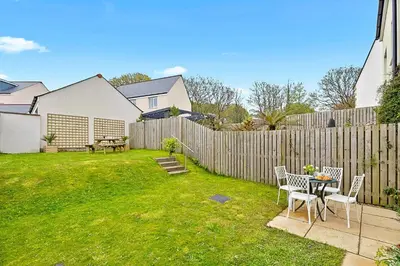 a backyard with a table and chairs and a fence at Finest Retreats - Cove House in St Austell