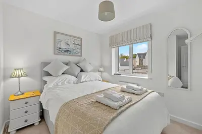 a white bedroom with a bed with two towels on it at Finest Retreats - Cove House in St Austell
