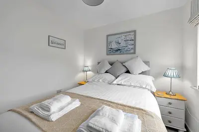 a bedroom with a bed with white sheets and pillows at Finest Retreats - Cove House in St Austell