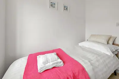 a bedroom with a bed with a pink blanket at Finest Retreats - Cove House in St Austell