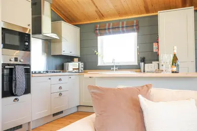 a kitchen with white cabinets and a couch in a room at 17 Meadow Retreat in Liskeard