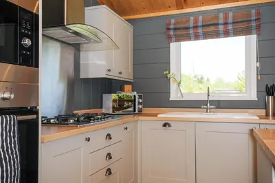 a kitchen with white cabinets and a sink and a window at 17 Meadow Retreat in Liskeard