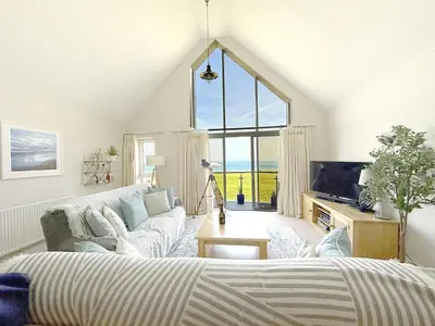 a living room with a bed and a large window at Penthouse at Bredon in Newquay