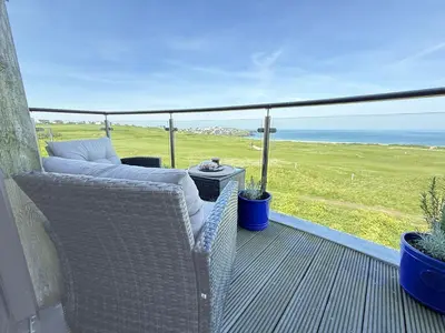 a balcony with wicker chairs and a view of the ocean at Penthouse at Bredon in Newquay
