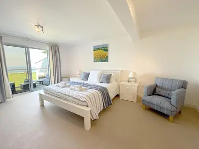 a bedroom with a bed and a chair at Penthouse at Bredon in Newquay