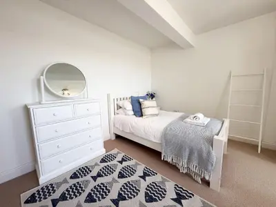 a bedroom with a bed and a dresser and a mirror at Penthouse at Bredon in Newquay