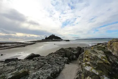 a beach with rocks and a house in the ocean at Old Temperance House in Saint Keverne