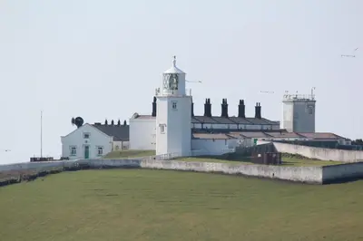 a lighthouse on a wall with a field in front of it at Old Temperance House in Saint Keverne