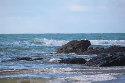 a beach with rocks and waves in the ocean at Old Temperance House in Saint Keverne